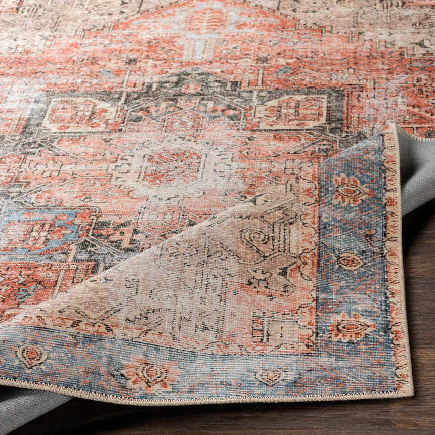 Close-up of the Livabliss Amelie AML-2309 washable area rug. Features a traditional, farmhouse design in beige, pink, blue and rust tones. Fold
