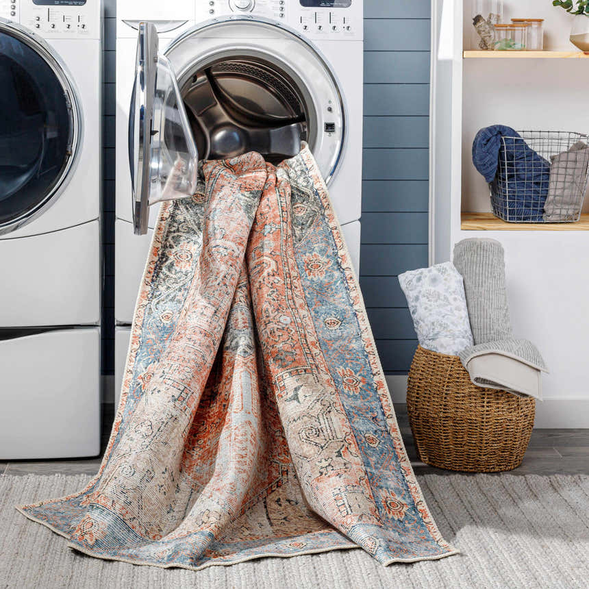 Laundry room scene with Livabliss Amelie AML-2309 washable rug draped over a washing machine. Beige, pink, and blue traditional pattern. Washing-Machine
