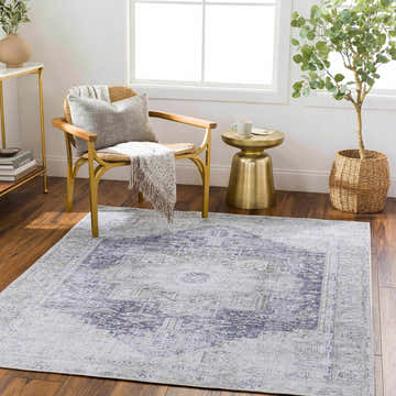 Living room scene with the Olive Rosman area rug, featuring cream, dark blue, and olive tones, under a chair and side table. Roomscene-Rectangle