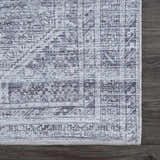 Close-up of the Barny Gray Blue Washable Rug showing its traditional pattern and charcoal and off-white color wash. Swatch