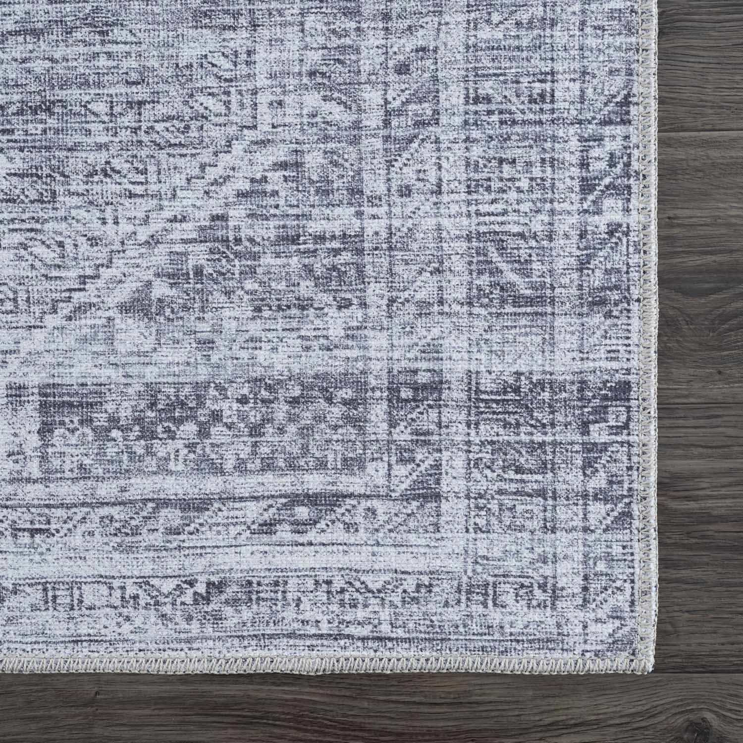 Close-up of the Barny Gray Blue Washable Rug showing its traditional pattern and charcoal and off-white color wash. Swatch