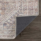 Close-up of the Barny Tan Washable Area Rug showing its traditional design, tan color wash, and gray backing. Fold