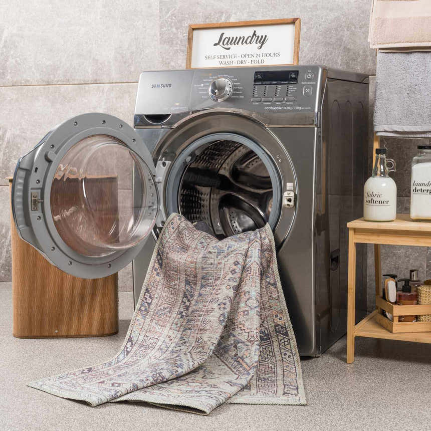 Laundry room scene with a Barny Tan Washable Area Rug partially inside a front-load washing machine. Washing-Machine