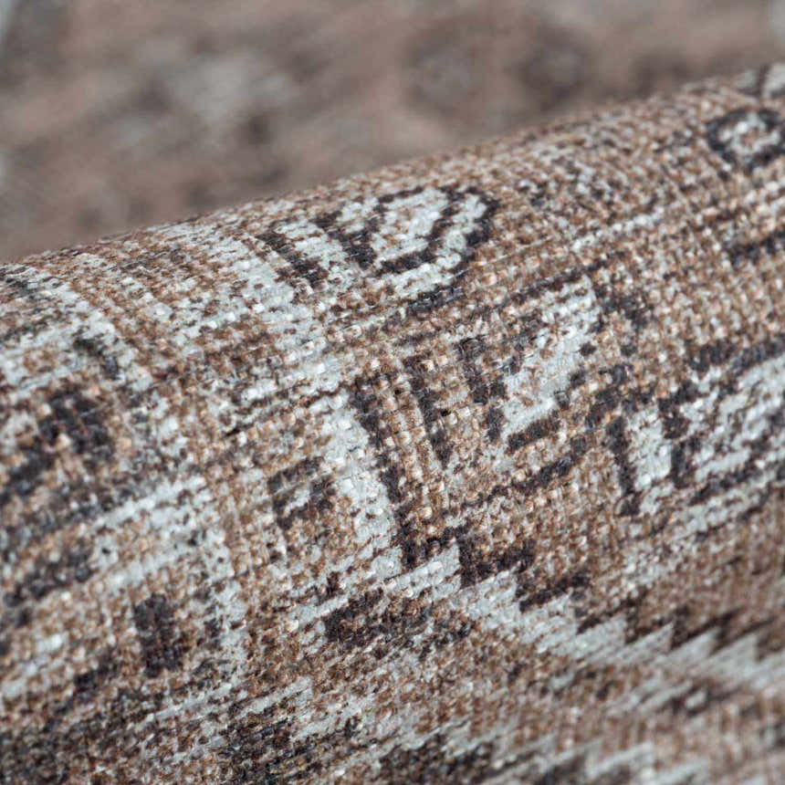 Close-up of the Barny Brown flat pile washable rug showing its brown, cream, and gray traditional pattern. Fold