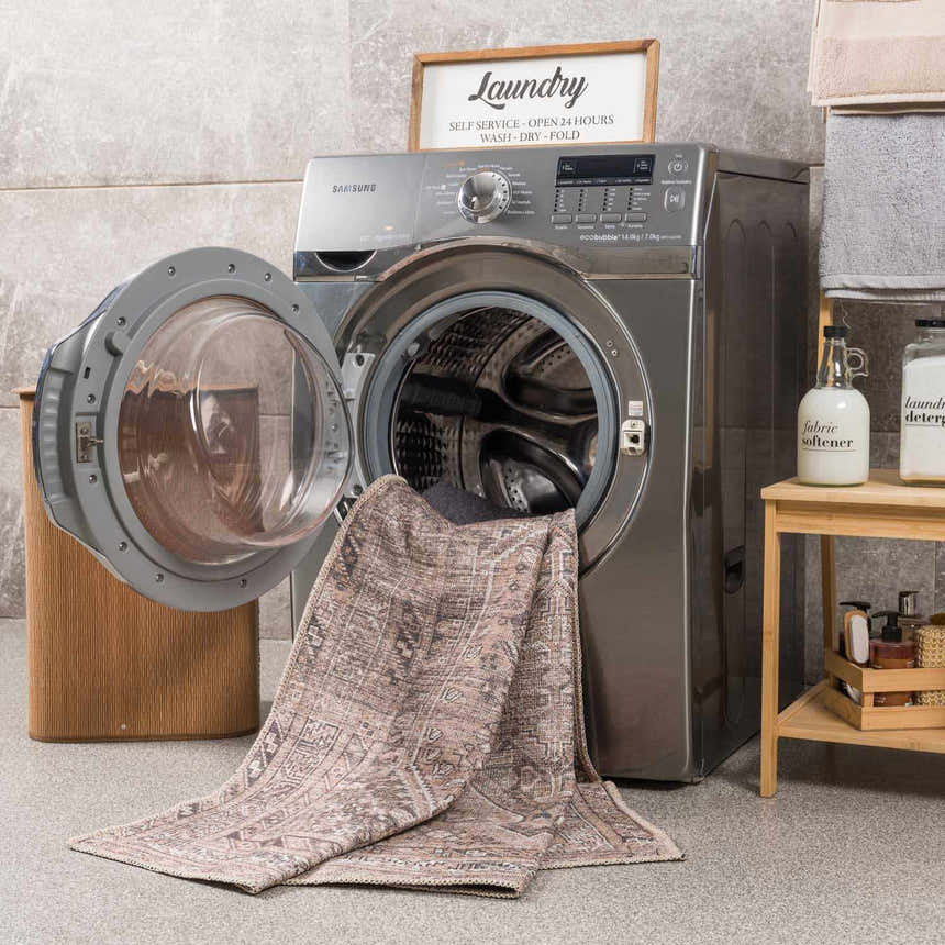 Laundry room scene with a Barny Brown flat pile washable rug partially inside a washing machine. Washing-Machine