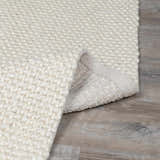 Close-up of the textured weave of the Lucerne Plain Cream Wool Rug, showing its looped pile and backing. Fold