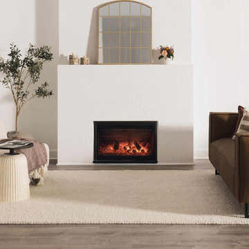Living room scene with a cream Lucerne Plain Wool Rug, fireplace, brown sofa, and neutral decor. Roomscene-Rectangle