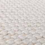 Close-up of the hand-woven texture of the Lucerne Plain Cream Wool Rug. Cream-colored wool rug with a basket weave pattern. Texture