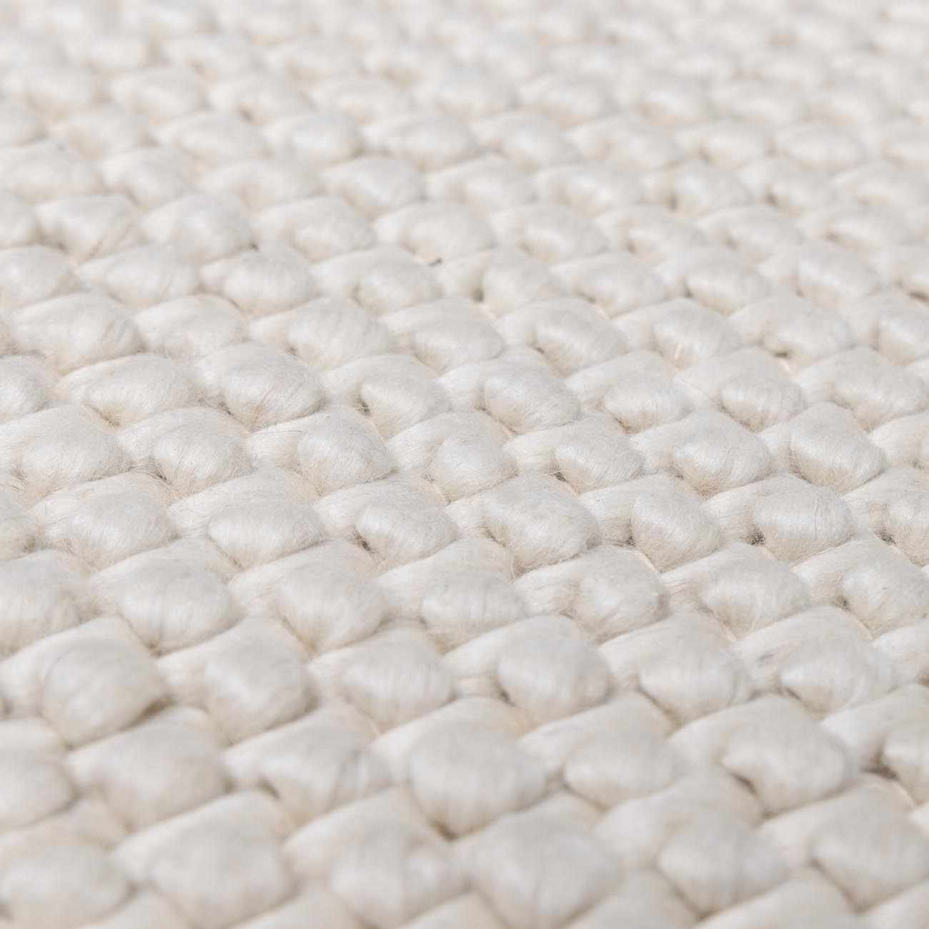 Close-up of the hand-woven texture of the Lucerne Plain Cream Wool Rug. Cream-colored wool rug with a basket weave pattern. Texture