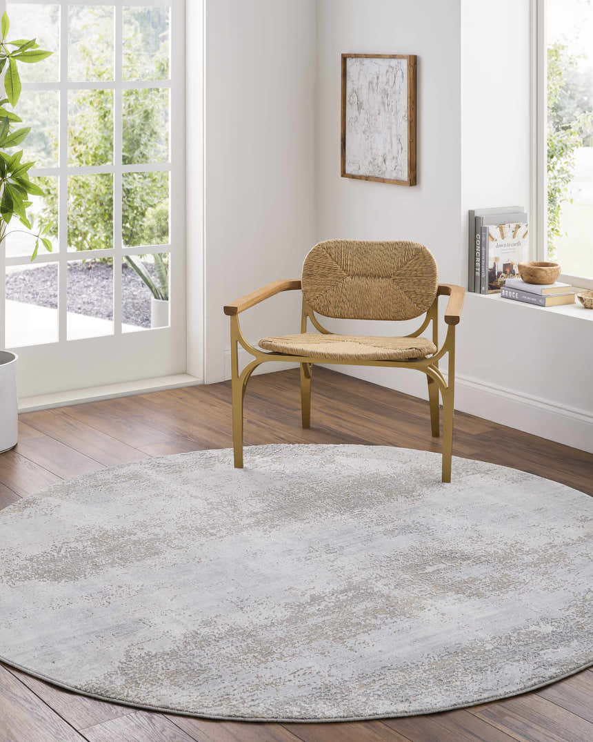 Light-filled room with a round Avani Thick Luxe Boutique Rug in gray tones under a woven chair. Roomscene-Round