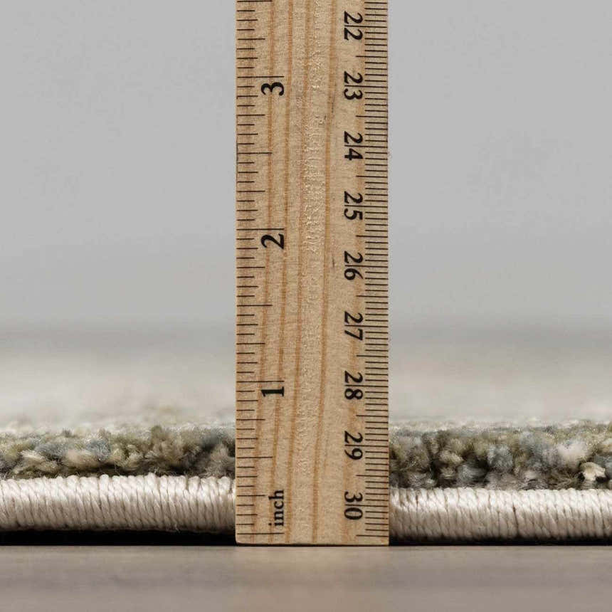 Close-up of the Zazie Thick Luxe Rug showing its pile height with a ruler. Colors: Beige, Gray, Olive. Pile