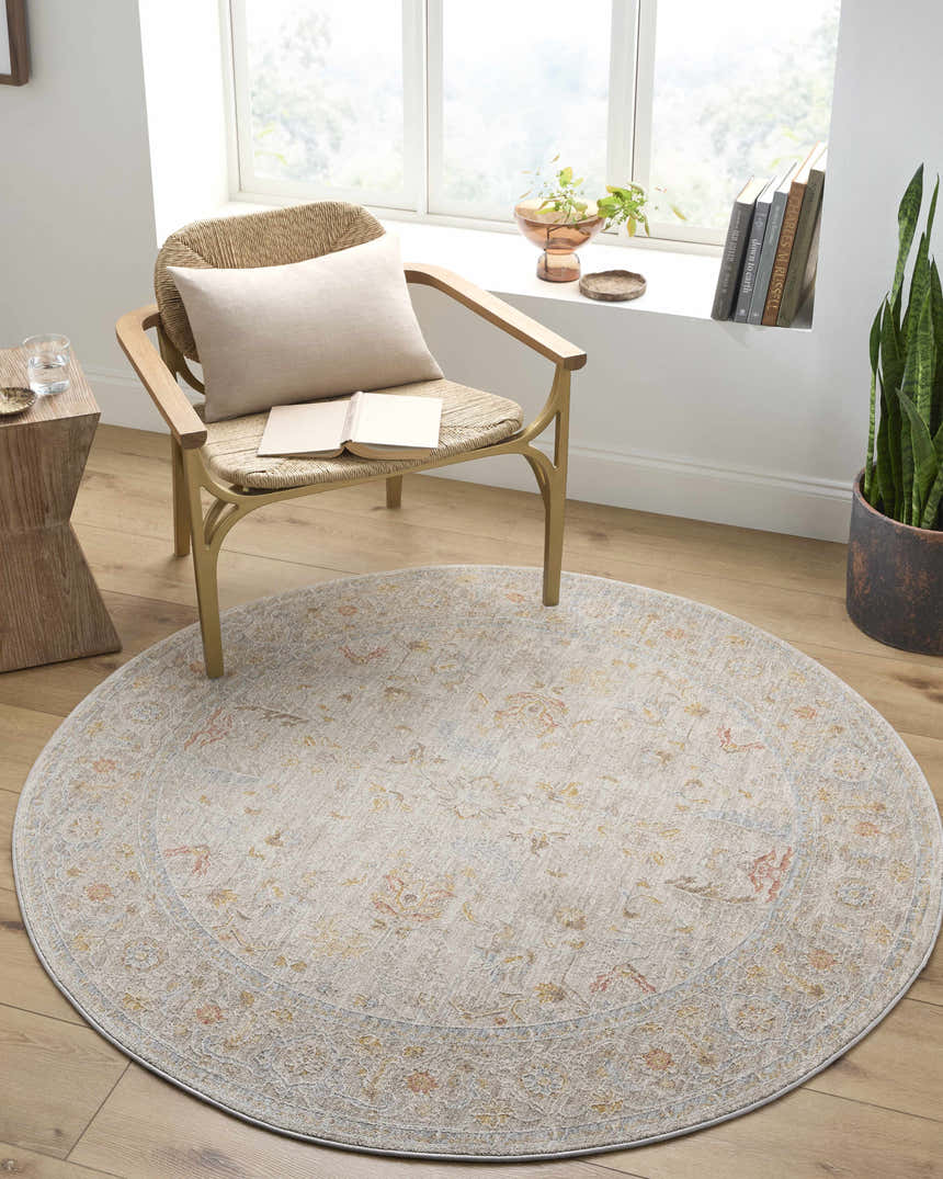 Sunlit reading nook with round Awena rug in amber, pink, and gray. Woven chair, wood floors, and potted plant create a cozy, transitional space. Roomscene-Round