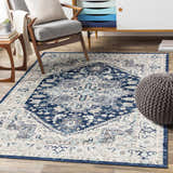 Living room scene with a Livabliss Chester rug in beige, charcoal, navy, and sky blue, styled with a chair and modern cabinet. Roomscene-Rectangle