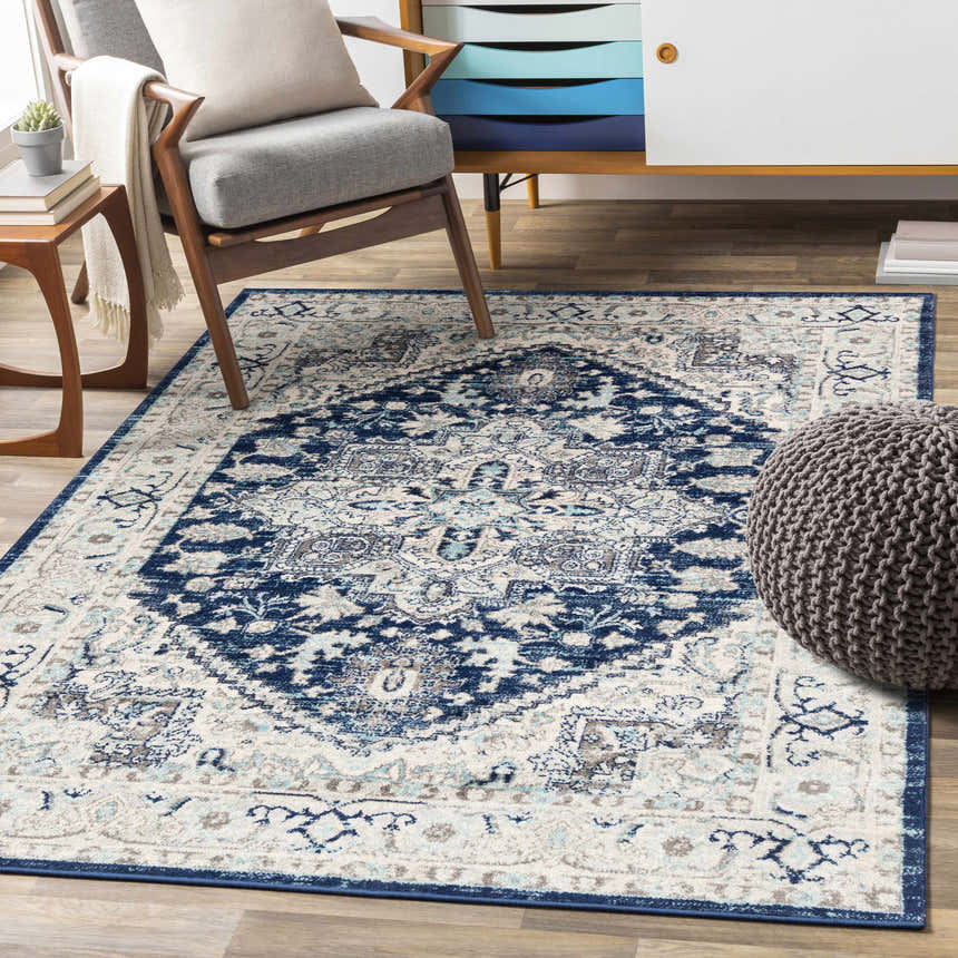 Living room scene with a Livabliss Chester rug in beige, charcoal, navy, and sky blue, styled with a chair and modern cabinet. Roomscene-Rectangle