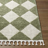 Close-up of Aitana Area Rug with cream and olive diamond pattern and tassel fringe on wood floor. Front