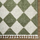 Close-up of the Aitana Area Rug featuring a cream and olive green diamond pattern and white tassels. Corner