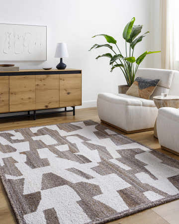 Living room with a Brendy Taupe Area Rug, light wood cabinet, and cream-colored armchairs. The rug has a geometric pattern. Roomscene-Rectangle