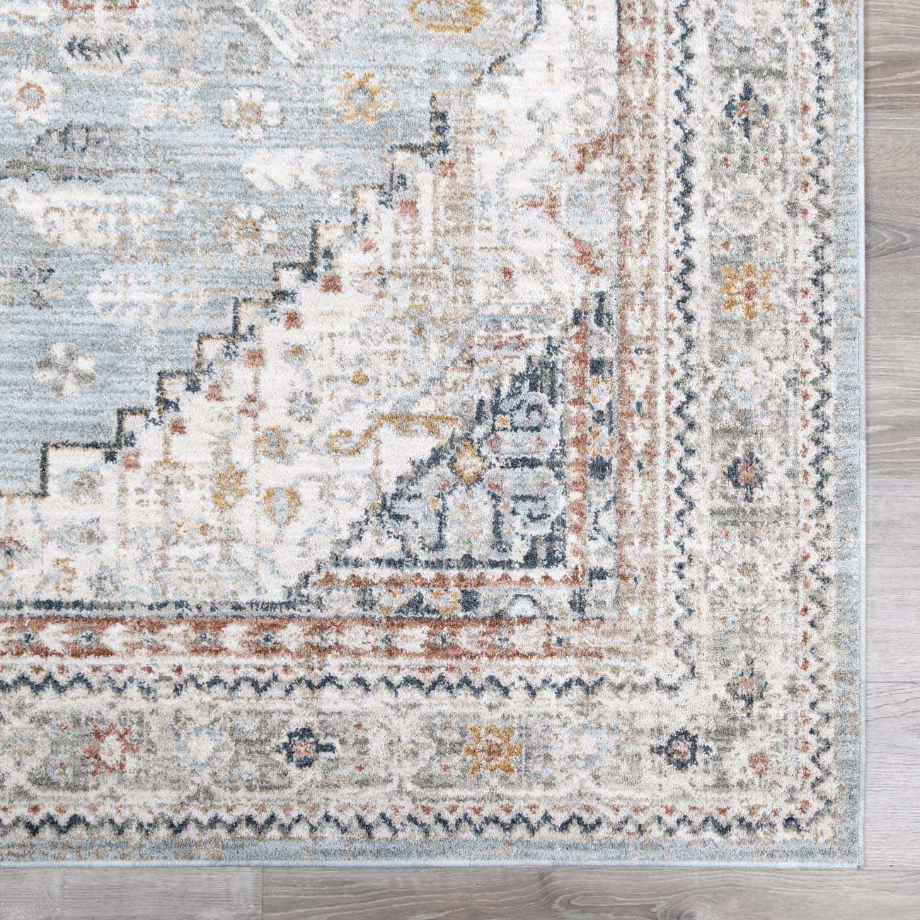 Close-up of the Kouta Gray Blue Area Rug. Features traditional patterns in beachhouse blue, beige, charcoal, and mustard tones. Swatch