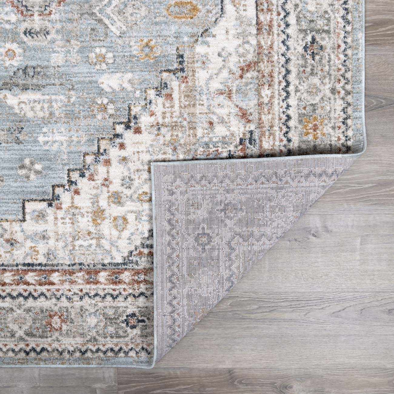 Close-up of the Kouta Gray Blue Area Rug showing its traditional pattern, soft texture, and durable machine-woven construction. Fold