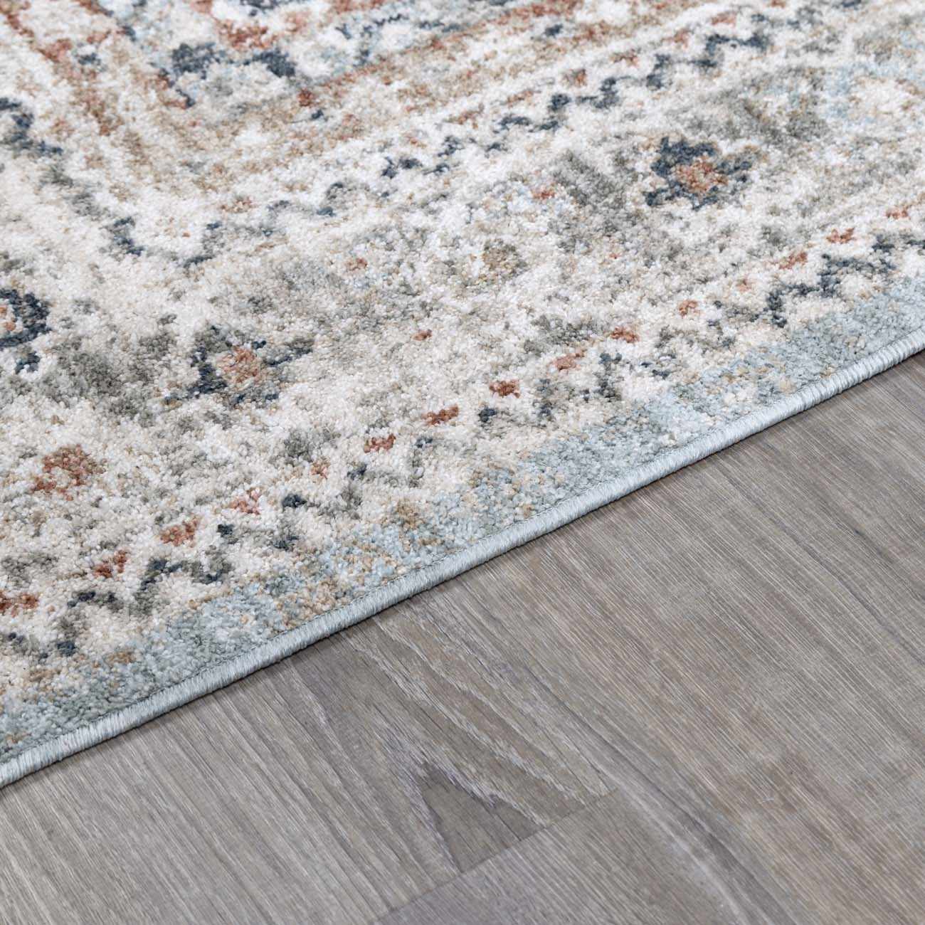 Close-up of the Kouta Gray Blue Area Rug showing its farmhouse-style pattern, soft texture, and colors like beige and ice blue. Pile