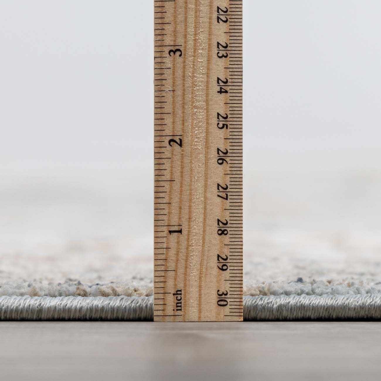 Close-up of Kouta Gray Blue Area Rug pile height, showing texture and rug thickness with a ruler. Pile