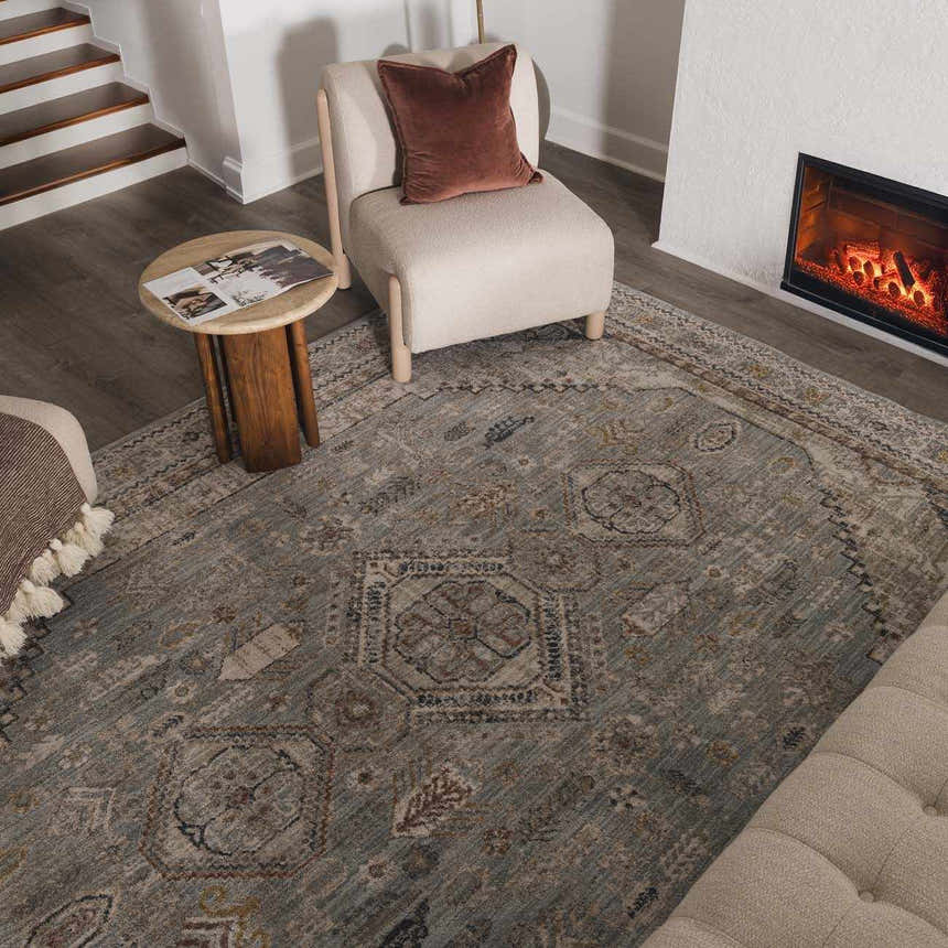 Living room scene with a Kouta Gray Blue area rug, beige chair, fireplace, and wood accents for a cozy, traditional feel. Roomscene-Rectangle