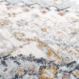 Close-up of the Kouta Gray Blue Area Rug. Features a traditional pattern in off-white, gray, blue, and mustard hues. Soft, textured weave. Texture