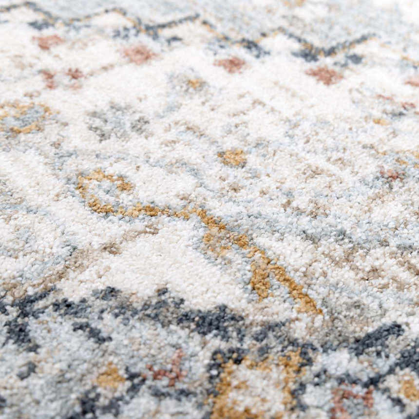 Close-up of the Kouta Gray Blue Area Rug. Features a traditional pattern in off-white, gray, blue, and mustard hues. Soft, textured weave. Texture