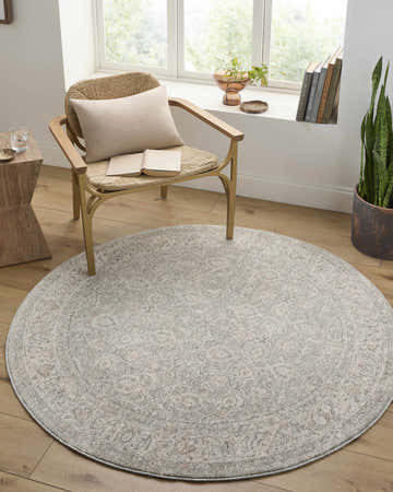 Cozy reading nook with a round Buddug Cream Area Rug, woven chair, wood floors, and natural light from the window. Roomscene-Round