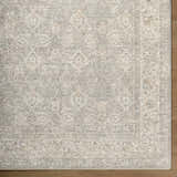 Close-up of the cream Buddug Area Rug showing a traditional, farmhouse pattern with sage and slate blue accents. Corner