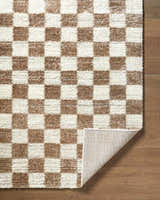 Close-up of Belita Cream Luxe Shag Area Rug. Cream and tan checkerboard pattern, plush texture, machine woven. Fold