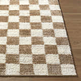 Close-up of Belita Cream Luxe Shag Area Rug with a checkerboard pattern in cream, ivory, and tan on a wood floor. Front