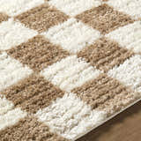 Close-up of the Belita Cream Luxe Shag Area Rug, featuring a cream and tan checkerboard pattern and plush shag texture. Texture