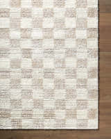 Close-up of Belita Beige Luxe Shag Area Rug. Cream and tan shag rug with a subtle checkerboard pattern on wood floor. Corner