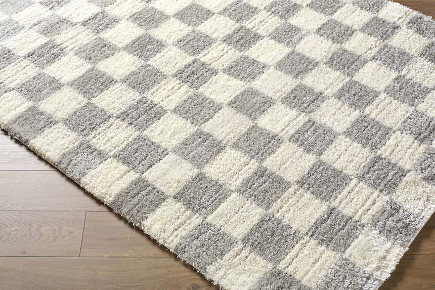 Close-up of the Belita Tan Luxe Shag Area Rug, showcasing its cream and light gray checkerboard pattern and soft, shag texture. Corner