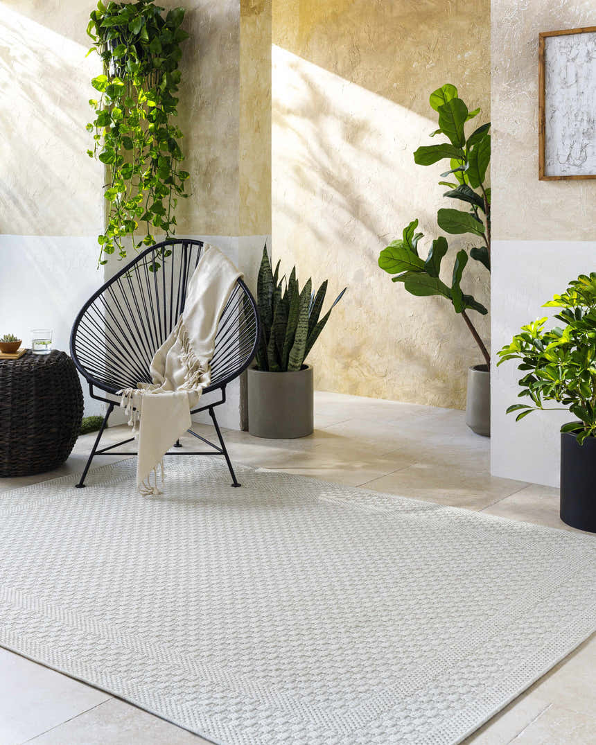 Sunlit patio scene with a light silver Brinda Area Rug, chair with throw, and potted plants creating a relaxing, contemporary space. Roomscene-Rectangle