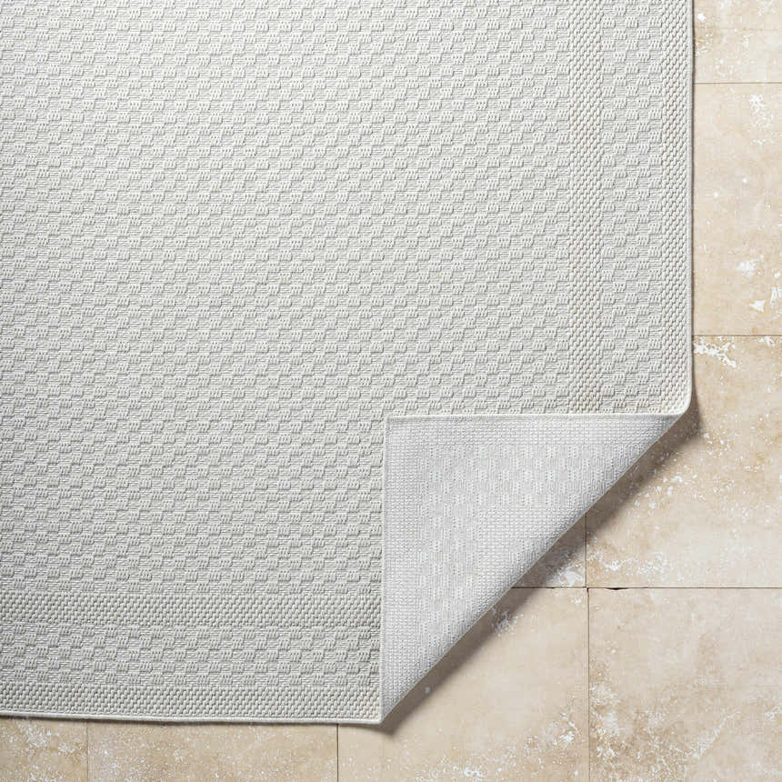 Close-up of the light silver Brinda Area Rug showing its woven texture and pattern on a beige tile floor. Fold