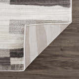 Close-up of Bojana Broken-Striped Area Rug showing geometric black, cream, and off-white pattern and rug backing. Fold