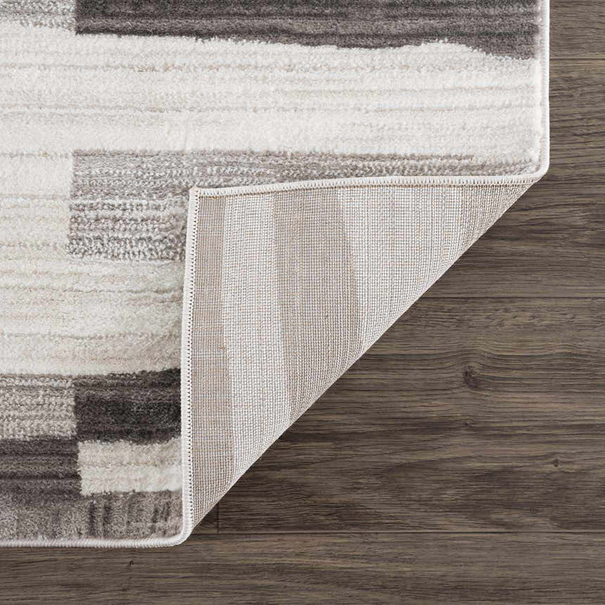 Close-up of Bojana Broken-Striped Area Rug showing geometric black, cream, and off-white pattern and rug backing. Fold