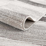Close-up of the Bojana Broken-Striped Area Rug showing its plush texture, cream, off white, and gray stripes. Fold