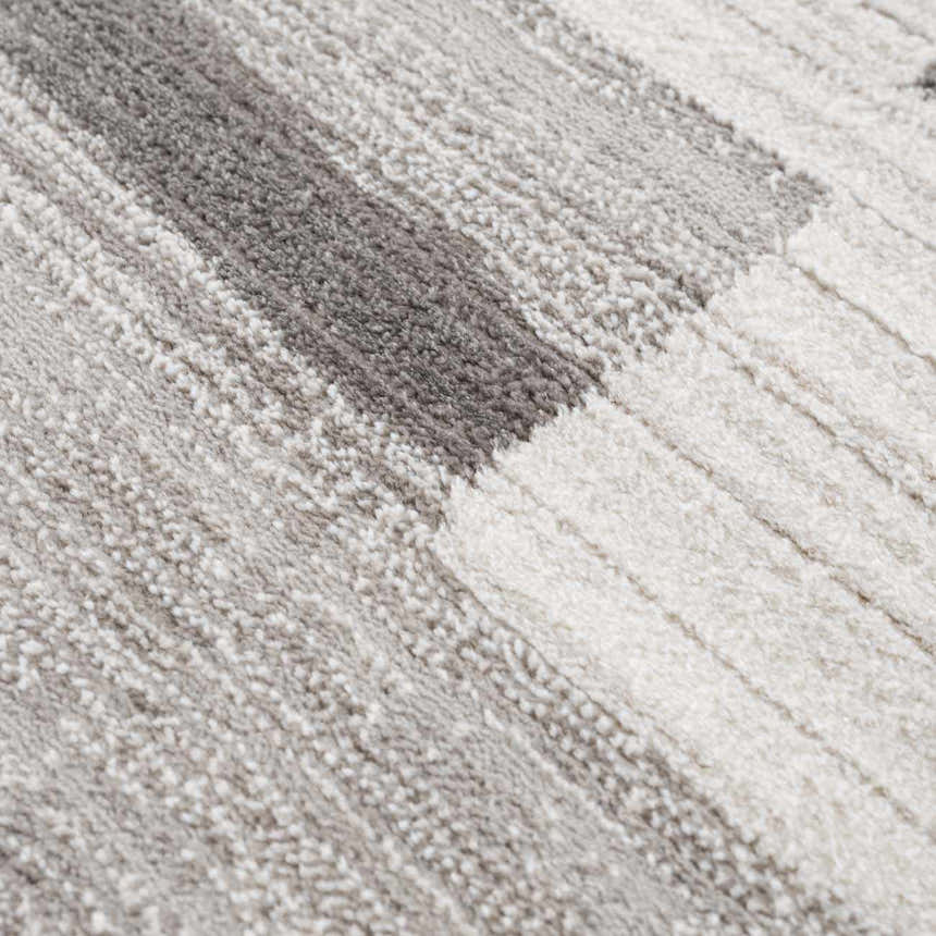 Close-up of the Bojana Broken-Striped Area Rug showing its cream, off-white, vizon, and black geometric pattern and soft texture. Texture