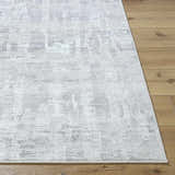 Close up of the Branka Area Rug showing its light silver and gray contemporary pattern on wood floors. Front