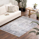 Living room scene with a Light Blue Holi-4603 washable rug, white sofa, wood floors, and houseplants. Roomscene-Rectangle