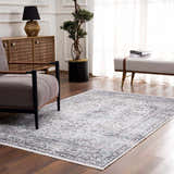 Living room scene with a Light Blue Holi-4603 washable area rug, gray armchair, wood cabinet, and neutral bench. Roomscene-Rectangle