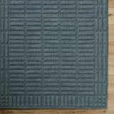 Close-up of the hand-tufted Birger Slate Blue Area Rug. The 100% wool rug features a contemporary geometric pattern. Corner