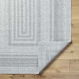 Close-up of the Bernal Area Rug, a machine-woven rug in medium gray and white with a traditional geometric pattern. Fold