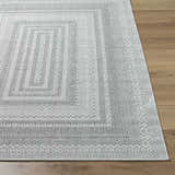 Close-up of the Bernal Area Rug, a medium gray and white rug with a traditional geometric pattern on wood flooring. Front