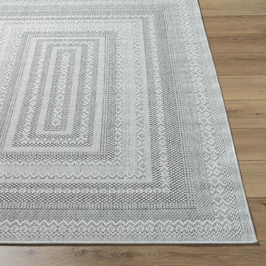 Close-up of the Bernal Area Rug, a medium gray and white rug with a traditional geometric pattern on wood flooring. Front