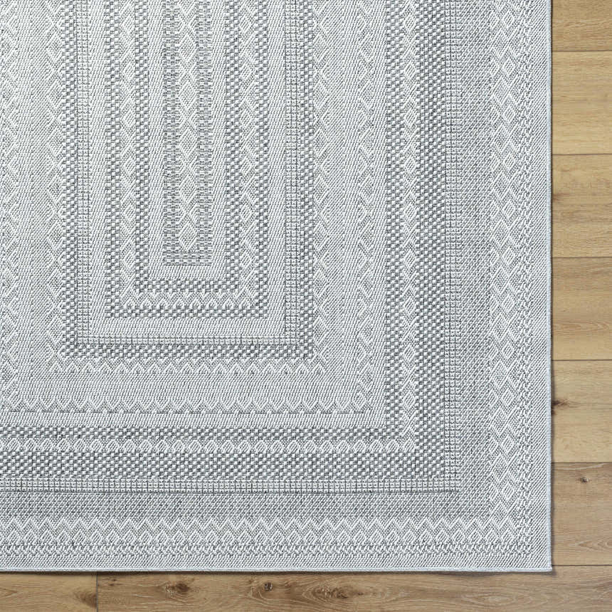 Close up of the Bernal Area Rug in medium gray and white with a geometric pattern. Corner