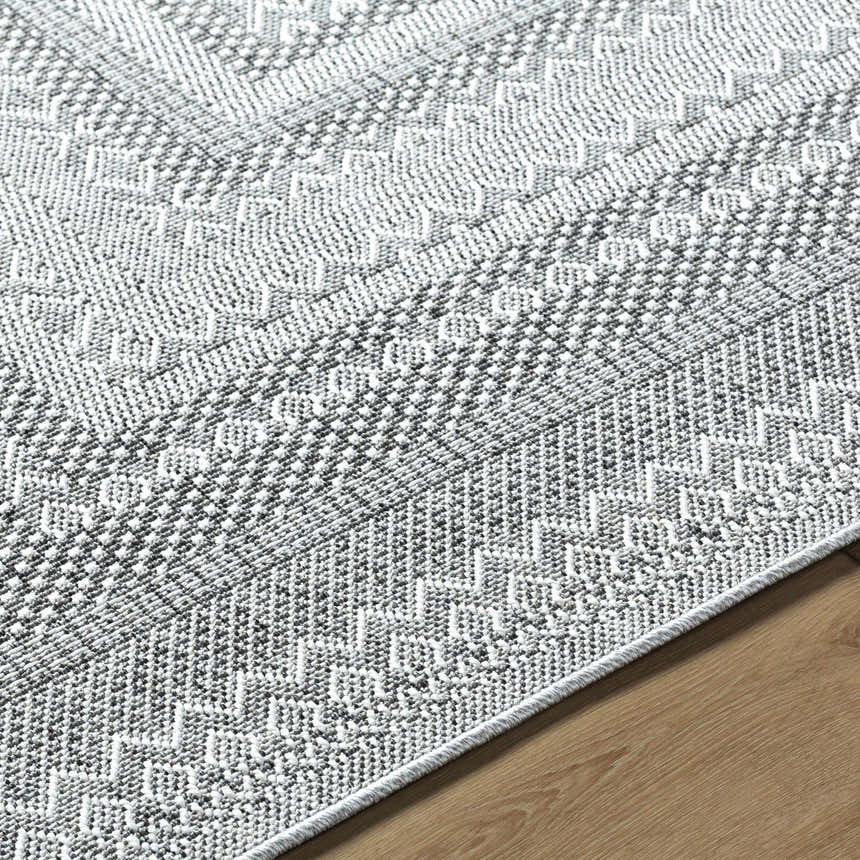 Close-up of the Bernal Area Rug. Gray and white woven rug with a geometric, farmhouse-style pattern. Texture